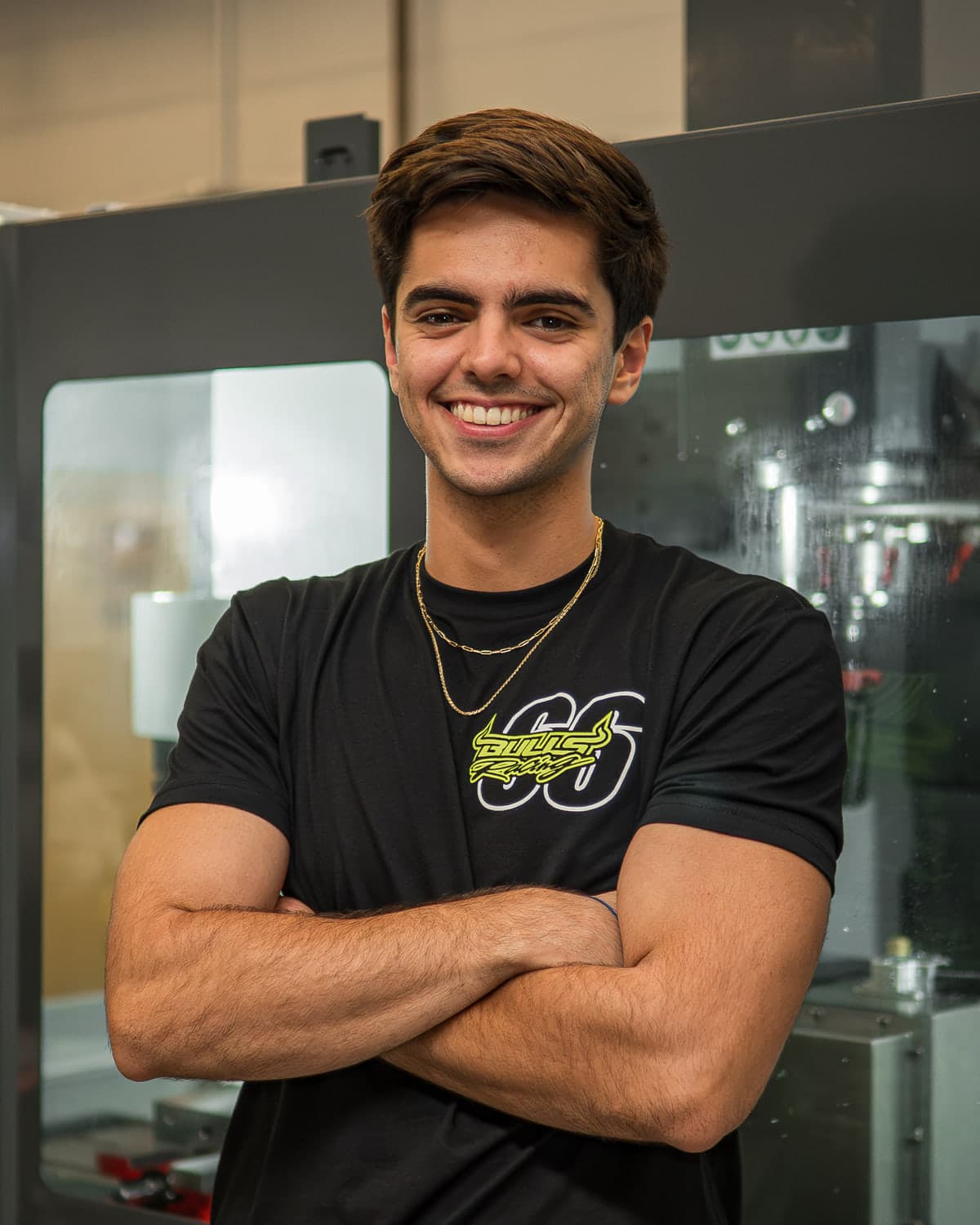 JP Medina Erse standing in the machine shop beside a CNC mill.